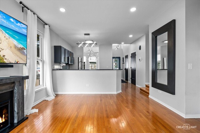 unfurnished living room with baseboards, light wood finished floors, and a lit fireplace