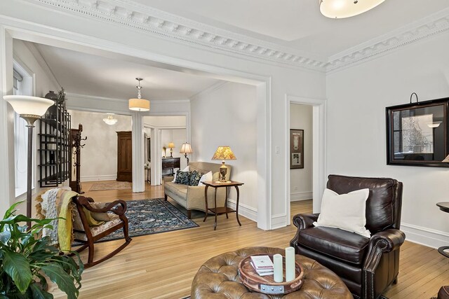 living area featuring light wood-type flooring, baseboards, ornamental molding, and stairway