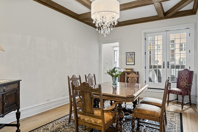 dining space with coffered ceiling, light wood-style floors, french doors, beamed ceiling, and a chandelier