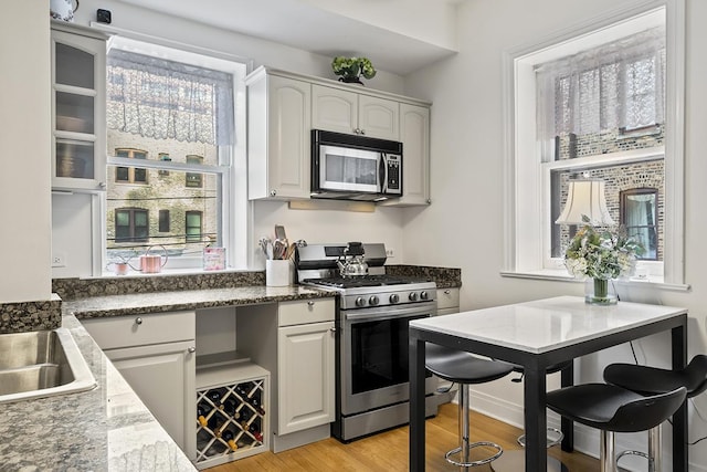 kitchen featuring stainless steel appliances, light wood-style floors, white cabinets, and a sink