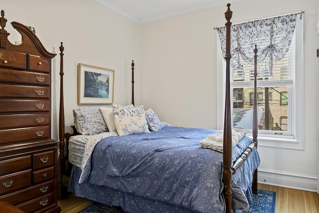 bedroom featuring baseboards, wood finished floors, and ornamental molding