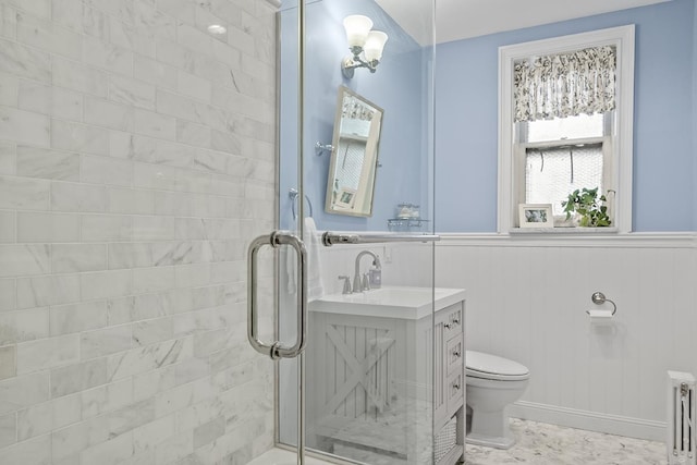 bathroom featuring radiator heating unit, toilet, a stall shower, vanity, and a wainscoted wall
