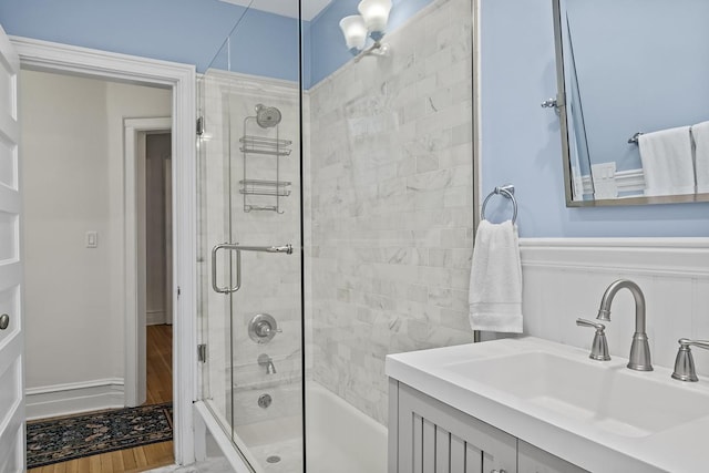 bathroom with shower / bath combination with glass door, wainscoting, and vanity