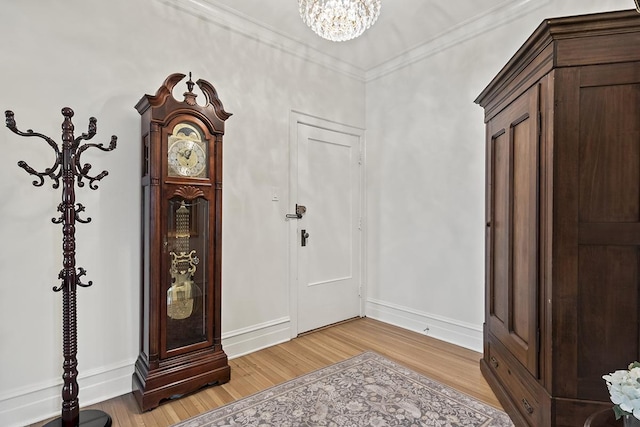 foyer with light wood-style floors, a chandelier, baseboards, and ornamental molding