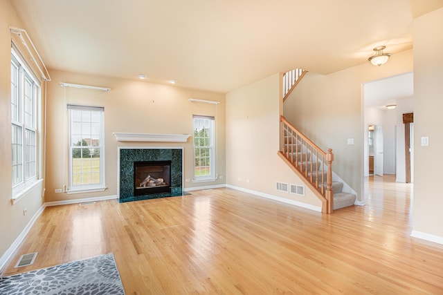 unfurnished living room with light wood-style floors, stairway, and visible vents