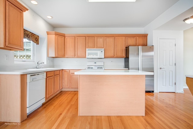 kitchen with white appliances, light countertops, a sink, and a kitchen island