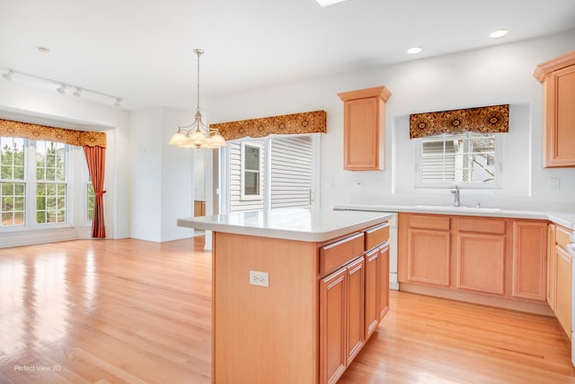kitchen with a chandelier, light countertops, light wood finished floors, a sink, and light brown cabinetry