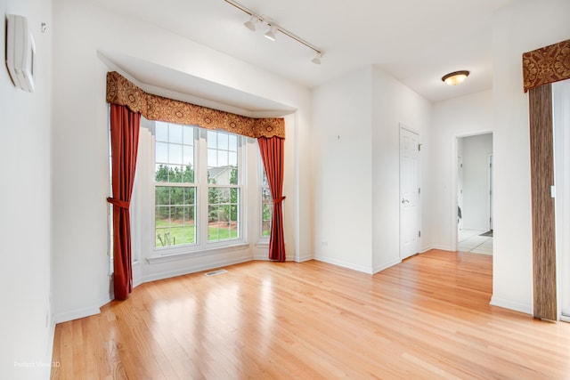 unfurnished room featuring visible vents, baseboards, light wood finished floors, and rail lighting