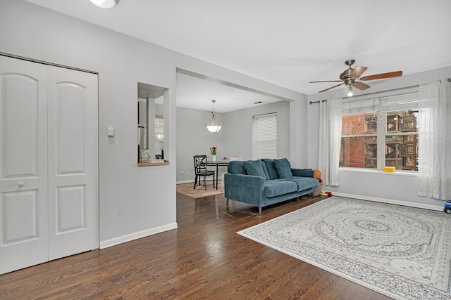 living area featuring baseboards, a ceiling fan, and wood finished floors