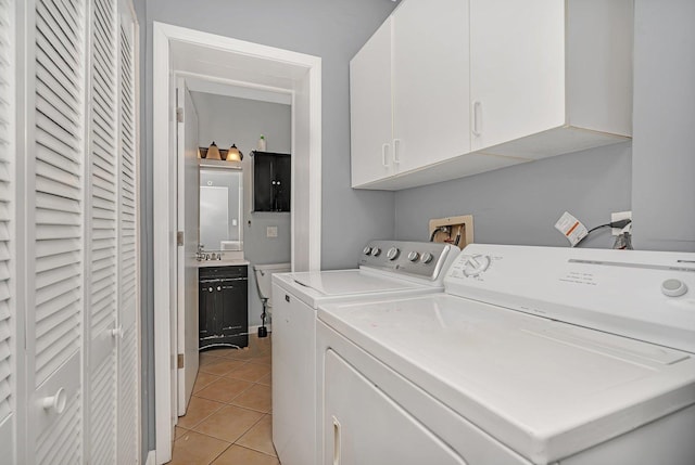 laundry area featuring washing machine and clothes dryer, cabinet space, and light tile patterned floors