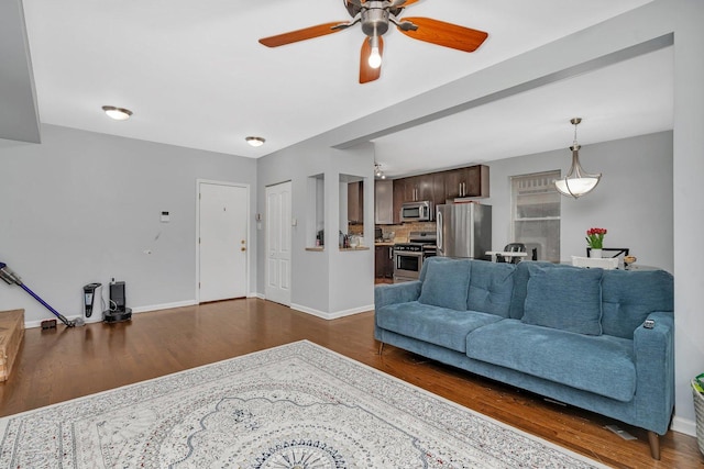 living area with dark wood-style flooring, baseboards, and a ceiling fan