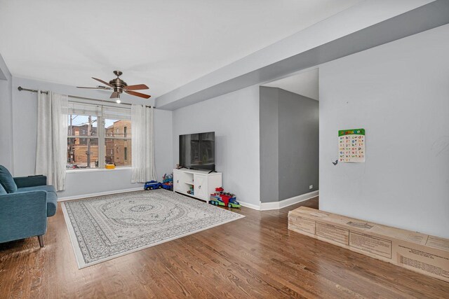 living room with wood finished floors, ceiling fan, and baseboards