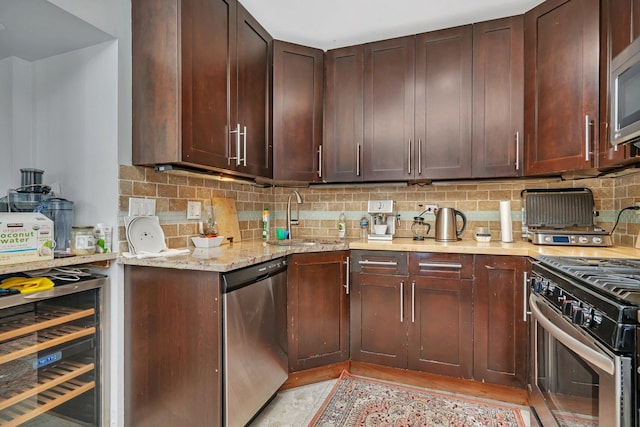 kitchen featuring wine cooler, a sink, backsplash, and appliances with stainless steel finishes