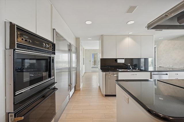 kitchen with white cabinets, dark countertops, a sink, and appliances with stainless steel finishes