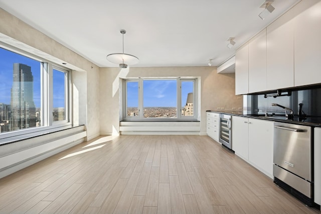 kitchen featuring dark countertops, plenty of natural light, beverage cooler, and dishwasher