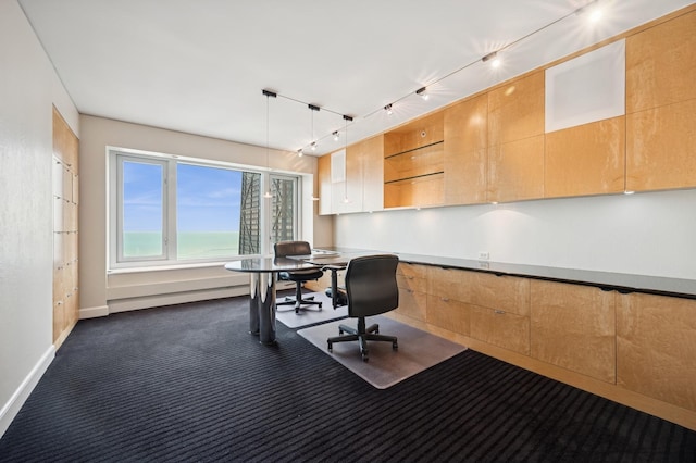 office area featuring track lighting, dark colored carpet, and baseboards
