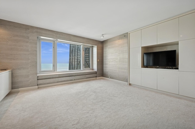 unfurnished living room with baseboards and carpet floors