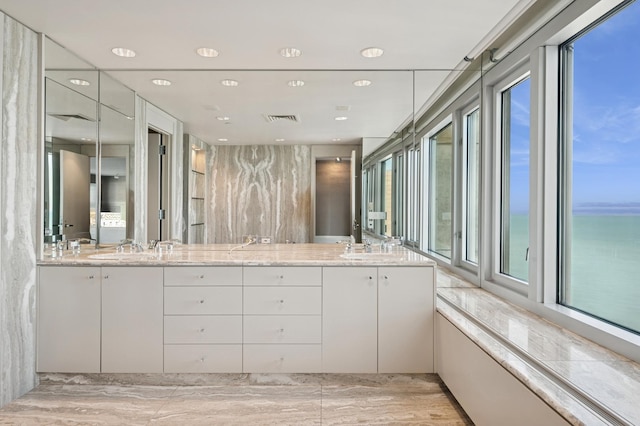 full bath with visible vents, a sink, double vanity, and a healthy amount of sunlight