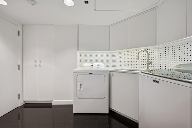 laundry room with dark tile patterned flooring, a sink, and cabinet space