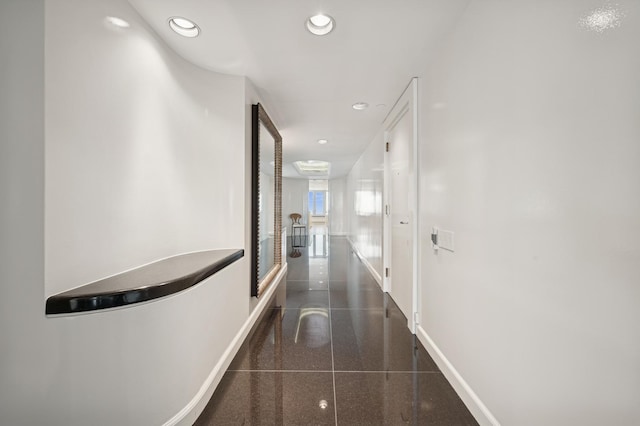 hallway with baseboards, granite finish floor, and recessed lighting