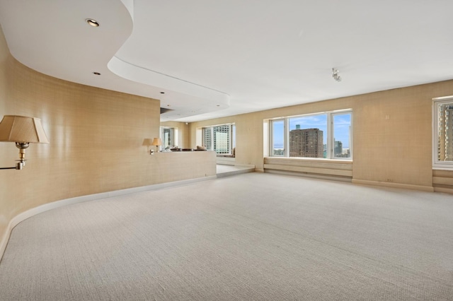 unfurnished living room with plenty of natural light, baseboards, and carpet floors