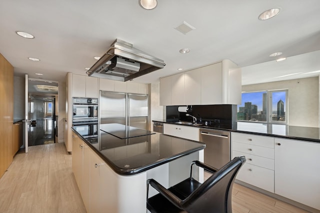 kitchen featuring a center island, dark countertops, light wood-style floors, extractor fan, and stainless steel appliances