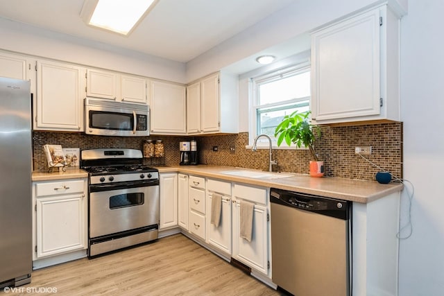 1164 Lakewood Cir, Naperville, IL 60540 - kitchen featuring appliances with stainless steel finishes, a sink, white cabinetry, light countertops, and backsplash