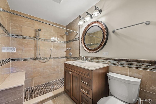 full bath featuring vanity, tile walls, a tile shower, and toilet