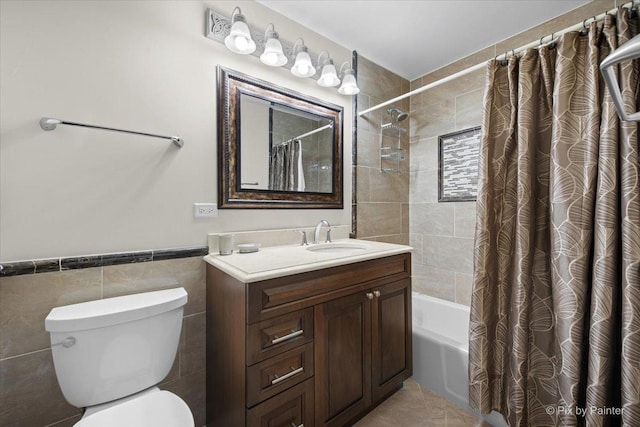 bathroom featuring vanity, toilet, shower / bathtub combination with curtain, wainscoting, and tile walls