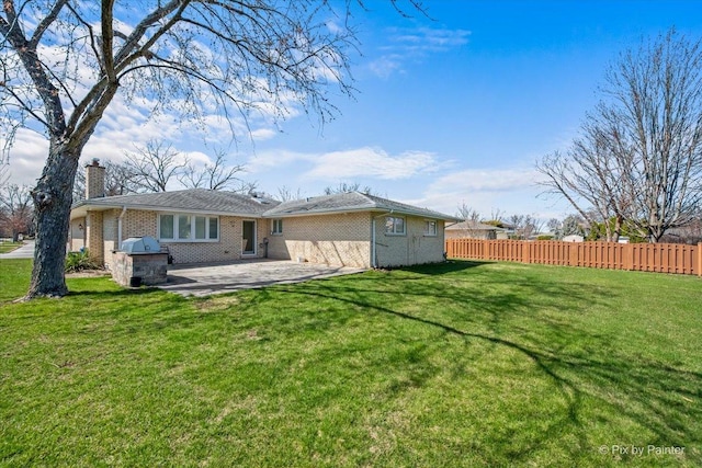 rear view of house featuring a chimney, a patio area, fence, and a yard