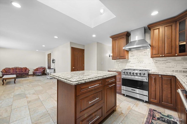 kitchen with tasteful backsplash, wall chimney range hood, high end stainless steel range, and recessed lighting