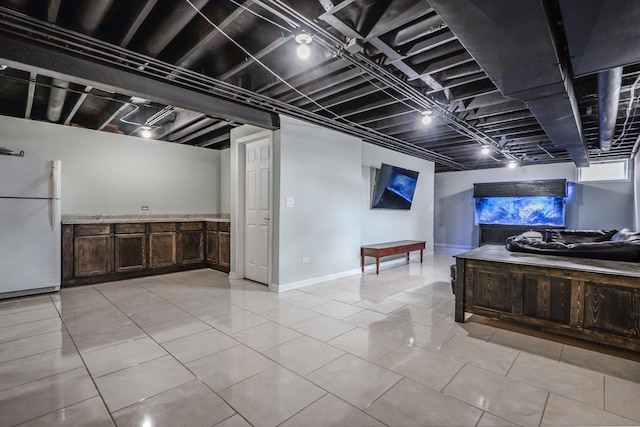 basement featuring freestanding refrigerator and light tile patterned floors