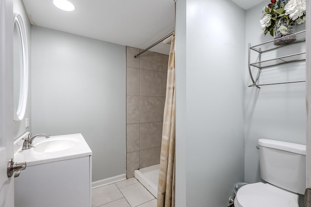 bathroom with vanity, tile patterned flooring, toilet, baseboards, and a tile shower