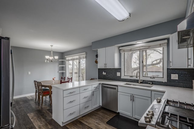kitchen featuring a sink, a peninsula, backsplash, and stainless steel appliances