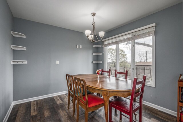 dining space featuring baseboards, a chandelier, and dark wood-type flooring