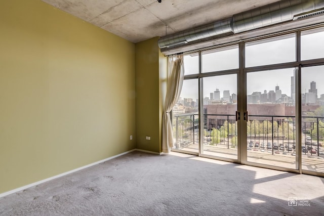 carpeted spare room with a view of city, baseboards, and expansive windows