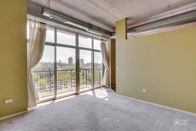 unfurnished room with a view of city, carpet flooring, visible vents, and baseboards