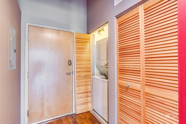 laundry area with electric panel, laundry area, stacked washer / dryer, and wood finished floors