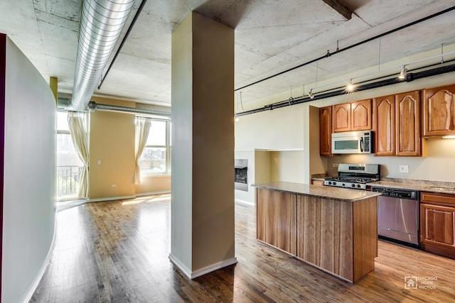 kitchen featuring stone countertops, wood finished floors, a center island, and stainless steel appliances
