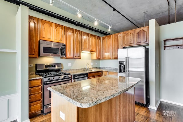 kitchen featuring a center island, light stone countertops, a sink, stainless steel appliances, and dark wood-type flooring