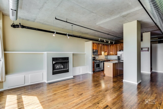 kitchen with brown cabinetry, open floor plan, appliances with stainless steel finishes, and rail lighting