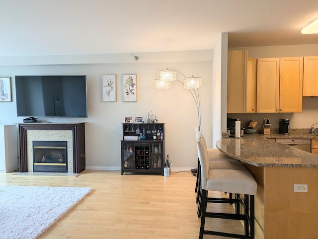33 W Ontario St Unit 40D, Chicago, IL 60654 - kitchen with dark stone countertops, light wood-style flooring, a breakfast bar, and light brown cabinets