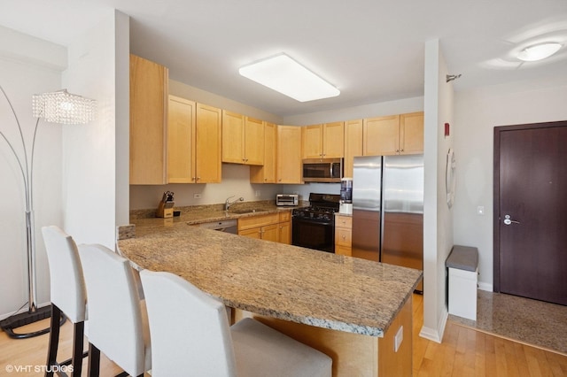 33 W Ontario St Unit 40D, Chicago, IL 60654 - kitchen with light brown cabinets, a sink, a peninsula, a kitchen bar, and stainless steel appliances