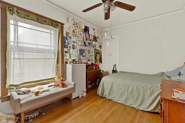 bedroom with light wood-style floors, crown molding, and ceiling fan