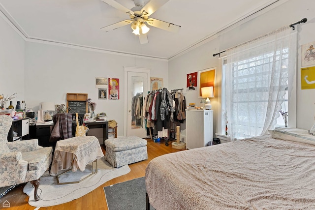 bedroom with crown molding, a ceiling fan, and wood finished floors