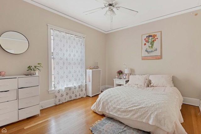 bedroom with light wood-type flooring, a ceiling fan, baseboards, and crown molding