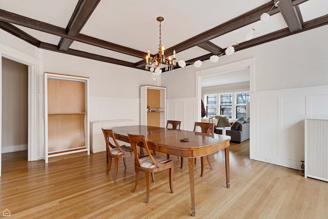 dining space with a decorative wall, coffered ceiling, light wood finished floors, and beam ceiling