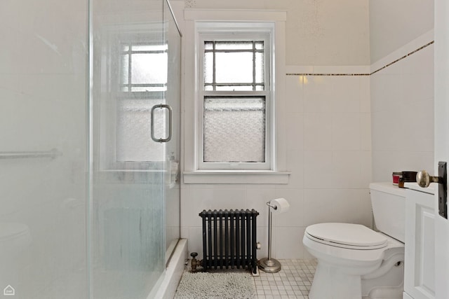 bathroom with radiator, a shower with shower door, toilet, and tile walls