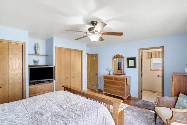 bedroom with multiple closets, a ceiling fan, wood finished floors, and baseboards
