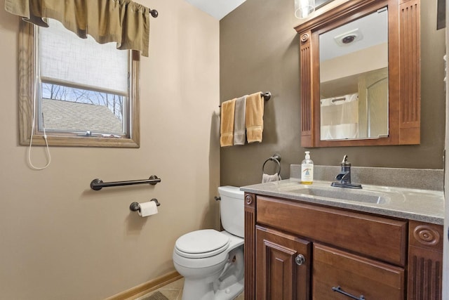 bathroom featuring toilet, tile patterned floors, vanity, and baseboards
